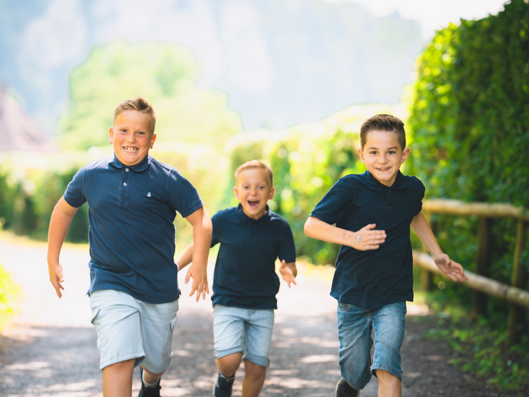 Drei Kinder laufen lachend bei einem Familienshooting in Vorarlberg